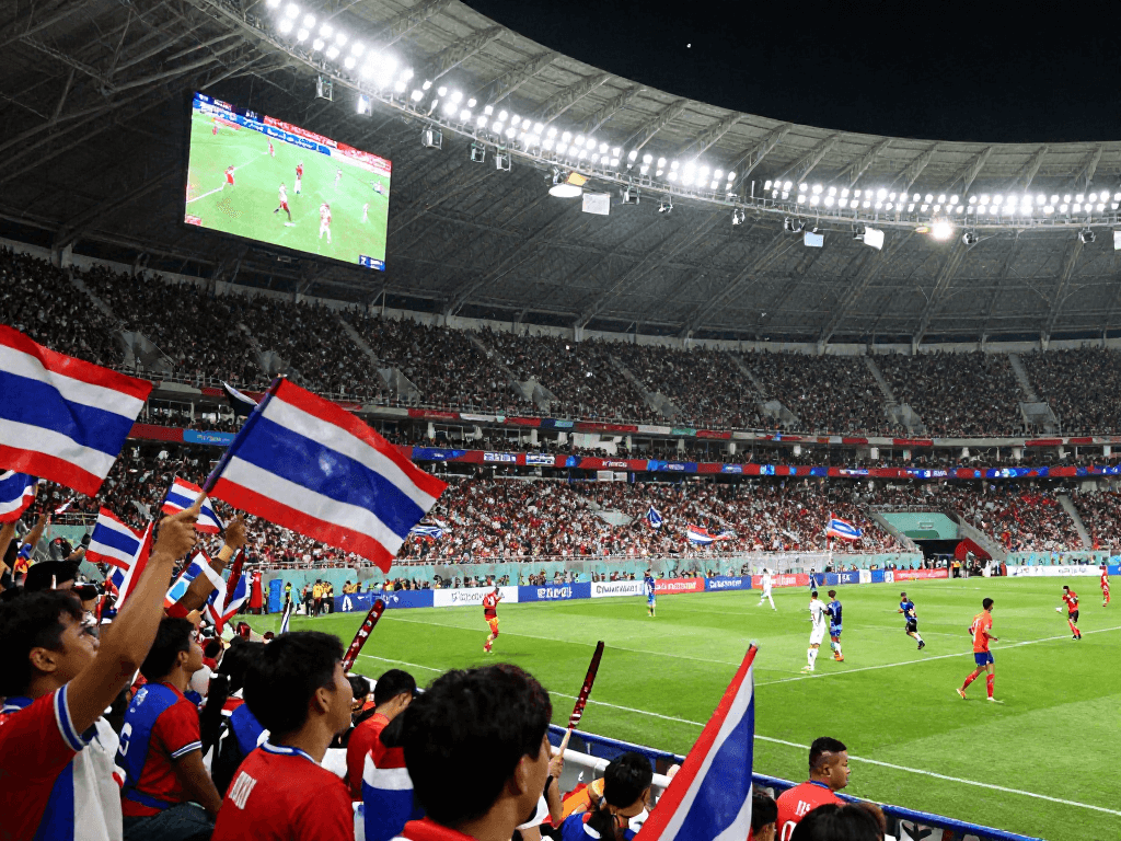 บรรยากาศการแข่งขันฟุตบอลโลกรอบชิง ราคาบอลโลกนัดชิง ในสนามที่เต็มไปด้วยแฟนบอลชาวไทยที่เชียร์ทีมชาติอย่างมีชีวิตชีวา